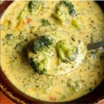 Bowl of homemade broccoli cheese soup with cheese and broccoli garnishes