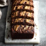 Slice of chocolate peanut butter banana bread on a wooden cutting board