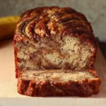Freshly baked cinnamon swirl banana bread loaf with banana slices on the side