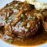Crock Pot cube steak simmering in delicious gravy, served on a plate
