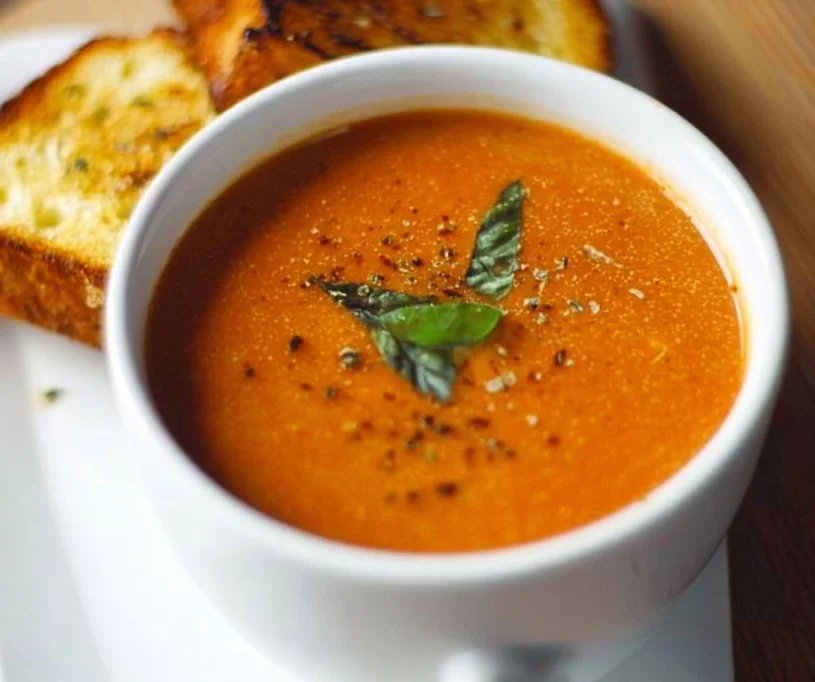 Bowl of roasted tomato basil soup garnished with fresh basil leaves