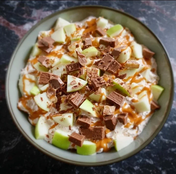 Delicious Snickers Apple Salad served in a bowl with apple slices and Snickers bars.