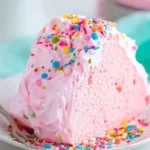 Slice of fluffy pink angel food cake with whipped cream and berries