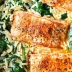 One Skillet Salmon served with Lemon Orzo on a plate garnished with herbs