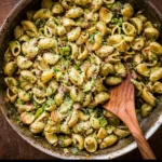 A bowl of vibrant pesto pasta with fresh ingredients and herbs