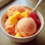 Bowl of vibrant Mango Strawberry Sorbet garnished with fresh strawberries.