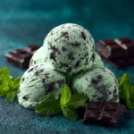 Bowl of mint chocolate chip ice cream topped with chocolate chips and mint leaves