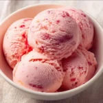 Creamy strawberry protein ice cream in a bowl topped with fresh strawberries