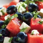 A vibrant watermelon blueberry feta salad in a bowl, showcasing fresh ingredients.