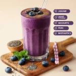 A healthy blueberry smoothie in a glass topped with fresh berries.
