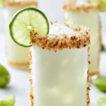 Coconut Lime Refresher drink in a glass with lime wedges and coconut slices