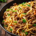 Plate of Mongolian ground beef noodles garnished with vegetables