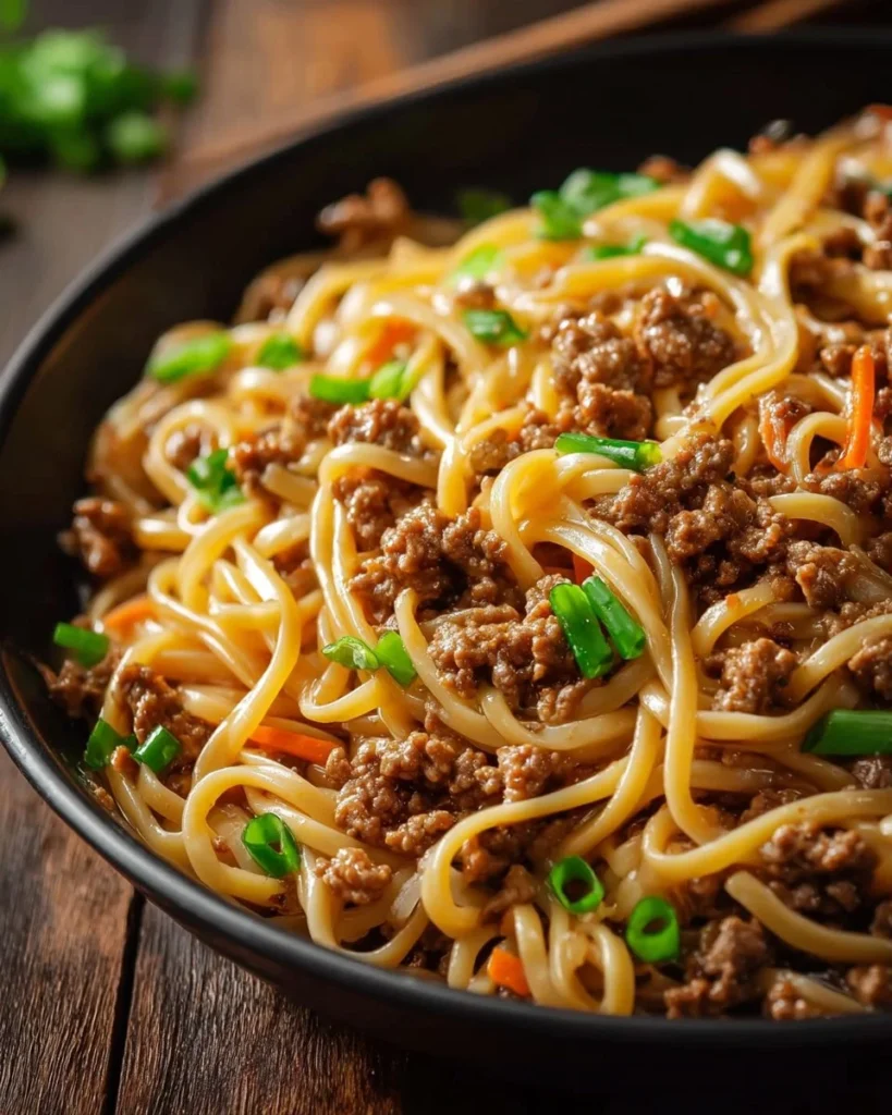 Plate of Mongolian ground beef noodles garnished with vegetables